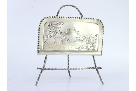 Porta guardanapos em prata com motivos marítimos gravados e assente sobre três pés.